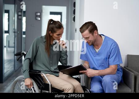 Doctor discussing with patient sitting in wheelchair Stock Photo