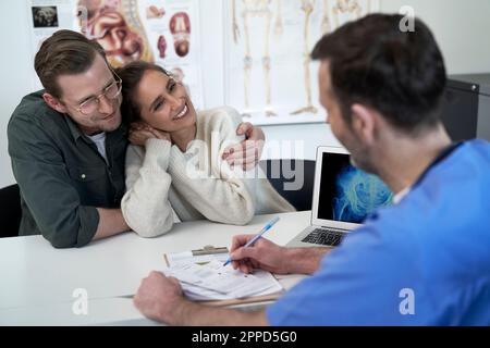 Happy couple with doctor discussing over prescription in clinic Stock Photo