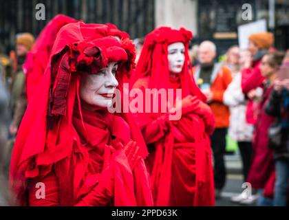 Red Rebel Brigade, performance activists march past the Houses of Parliament/Westminster as part of 'The Big One' Extinction Rebellion protest April. Stock Photo