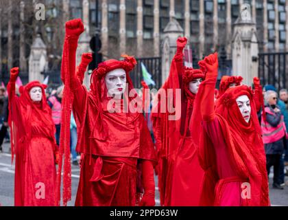 Red Rebel Brigade, performance activists march past the Houses of Parliament/Westminster as part of 'The Big One' Extinction Rebellion protest April. Stock Photo