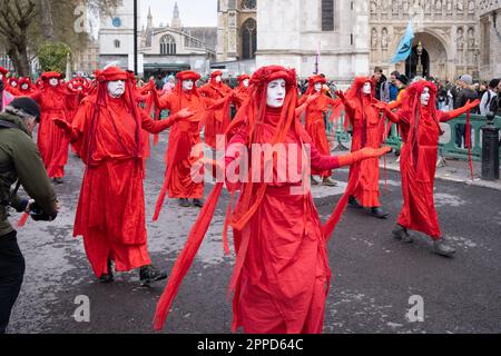 Red Rebel Brigade, performance activists march past the Houses of Parliament/Westminster as part of 'The Big One' Extinction Rebellion protest April. Stock Photo