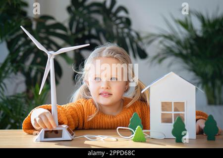 Cute girl operating wind turbine model at home Stock Photo