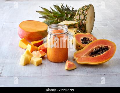 Halved mango fruit, papaya, pineapple and smoothie in jar Stock Photo