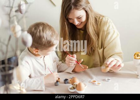 Happy mother and son decorating Easter eggs at home Stock Photo
