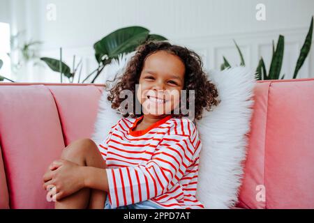Happy cute girl sitting on sofa at home Stock Photo