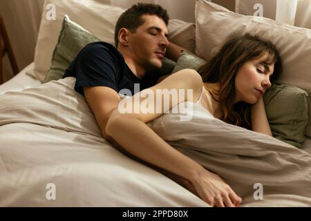 Couple with eyes closed sleeping in bed together Stock Photo