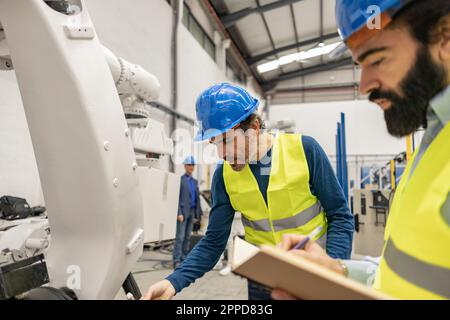 Engineers working on robotic arm in industry Stock Photo
