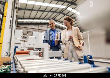 Smiling engineers having discussion over machinery in factory Stock Photo