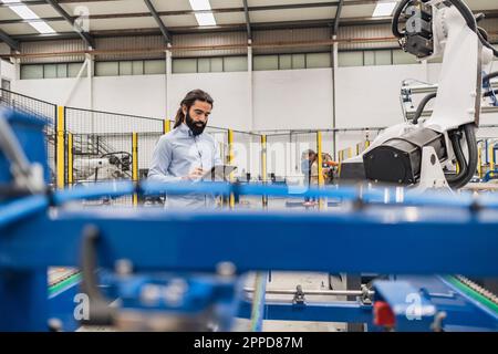 Engineer using tablet PC by robotic arm Stock Photo