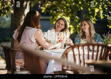 Smiling women enjoying drinks sitting at dining table in restaurant Stock Photo