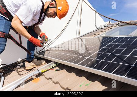 Young engineer with work tool installing solar panels Stock Photo