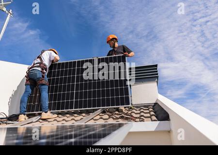 Engineers together installing solar panels on roof Stock Photo