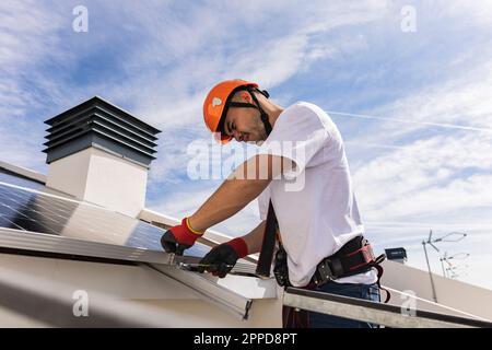 Young engineer wearing hardhat installing solar panels Stock Photo