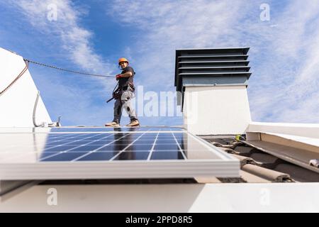 Engineer wearing safety harness walking on roof Stock Photo
