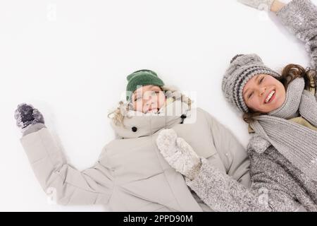 Happy friends lying down and enjoying in snow Stock Photo