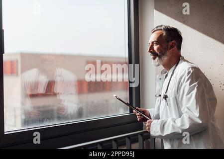 Smiling doctor looking through window Stock Photo