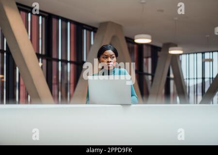 Thoughtful businesswoman with laptop by railing Stock Photo