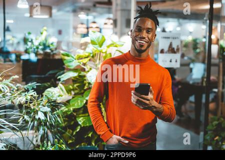Happy young businessman holding mobile phone in office Stock Photo