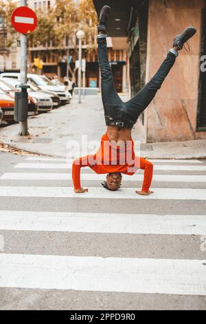 Carefree young man doing headstand on zebra crossing Stock Photo