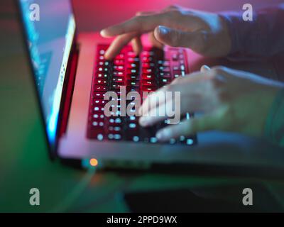 Hacker typing on illuminated laptop keyboard at office Stock Photo