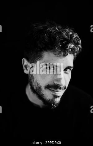 Smiling young man with beard against black background Stock Photo