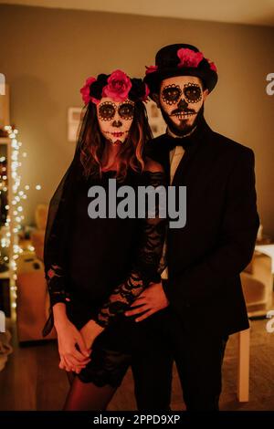 Couple wearing Day of the Dead costumes standing at home Stock Photo