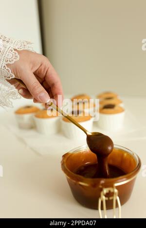 Hand of woman holding spoon of salted caramel in bowl Stock Photo