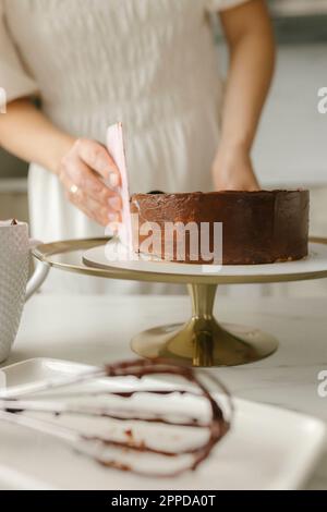 Young woman leveling sides of cake at home Stock Photo