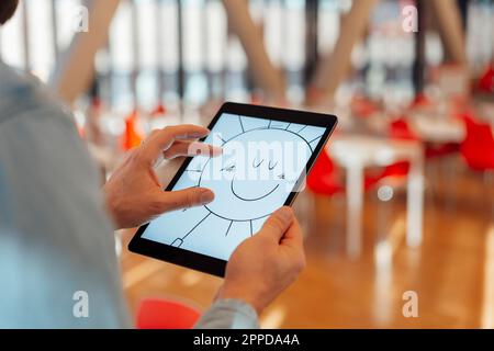 Businessman zooming design of sun on tablet PC in office Stock Photo