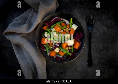 Bowl of ready-to-eat vegetarian salad with sweet potato, celery, radicchio, green beans, croutons, walnuts and parsley Stock Photo