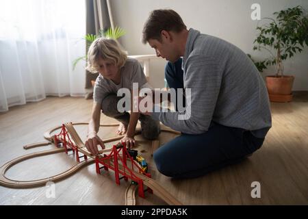 Father and son playing together with toy train at home Stock Photo