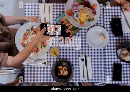 Young woman photographing food through smart phone Stock Photo