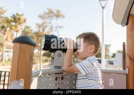 Boy looking through telescope at playground Stock Photo