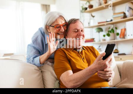 Happy senior couple on video call through smart phone at home Stock Photo
