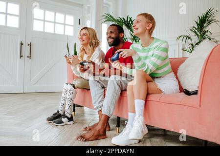 Happy young man playing video game with women sitting on sofa at home Stock Photo