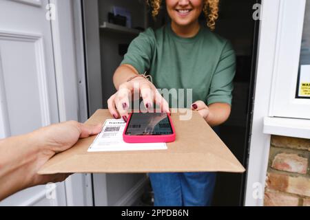 Happy woman using smart phone and taking delivery of package Stock Photo