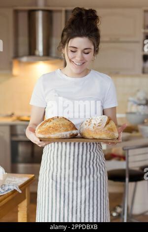 Happy woman holding freshly baked loafs of bread Stock Photo