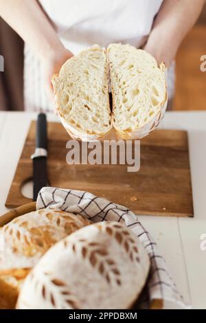 Woman holding sliced sourdough bread at home Stock Photo