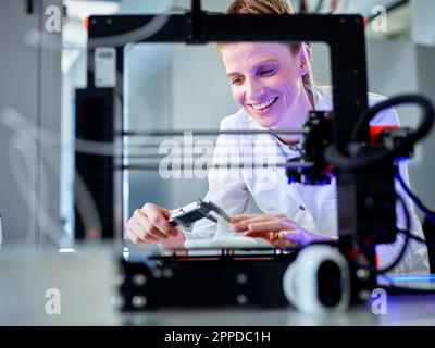 Happy engineer operating 3D printing machine in laboratory Stock Photo