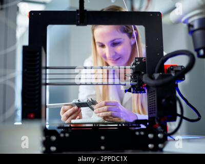 Smiling engineer with vernier calliper operating 3D printing machine Stock Photo