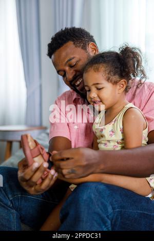 Father helping daughter in wearing shoes at home Stock Photo