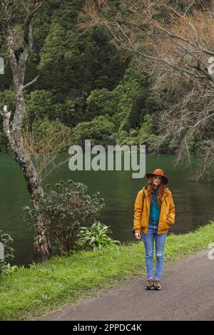 Woman wearing hat standing on road by lake Stock Photo