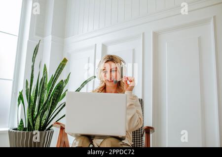 Smiling freelancer wearing headset using laptop at home Stock Photo