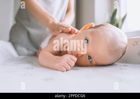 Baby boy lying on changing table with mother in background at home Stock Photo