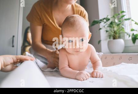 Sister helping mother taking care of baby at home Stock Photo