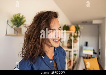 Happy young man with long hair at home Stock Photo