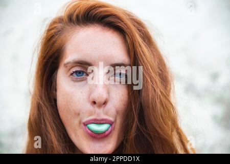 Young redhead woman chewing bubble gum Stock Photo