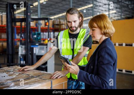 Manager sharing tablet PC with colleague by stocks in warehouse Stock Photo