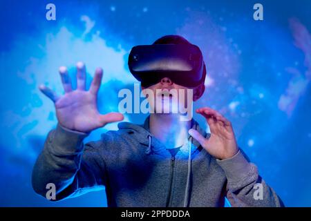 Shocked young man wearing virtual reality glasses standing in front of projection screen Stock Photo