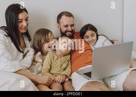 Smiling family using laptop together at home Stock Photo